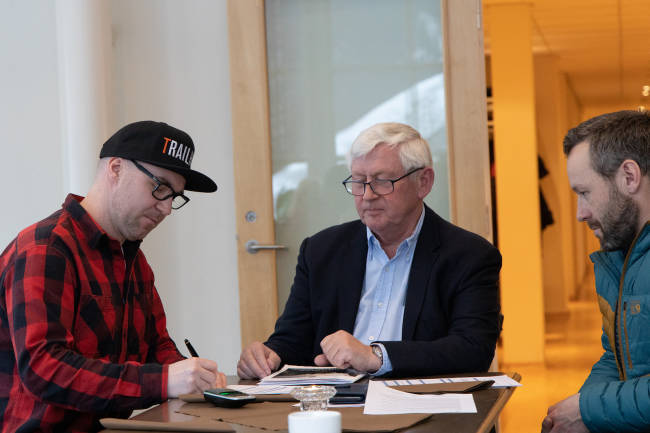 Knut Lønnqvist (til venstre) og Ove Grøndal (til høyre) i Trailhead Nesbyen undertegnet kontrakten med Norges flotteste sykkelopplevelse ved Osmund Ueland. Foto: Norges flotteste sykkelopplevelse