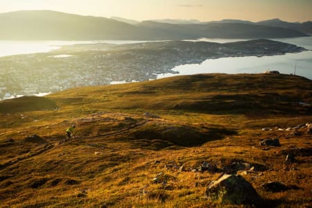 Stien går fra toppen Bønntua ned til Fjellheisen (til høyre i bildet) for så å traversere tilbake og ned til Tromsø. / Stisykling i Norge.