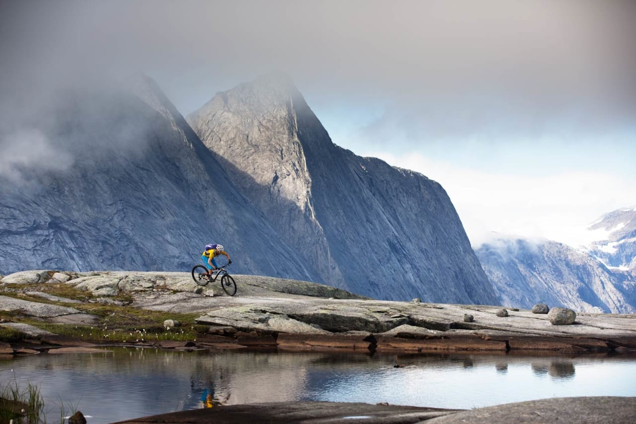 Per-Eivind Syvertsen sykler blant helt andre omgivelser enn han er vant til fra hjembyen Kongsberg. Isbreen Frostisen skimtes såvidt i bakgrunnen. / Stisykling i Norge.