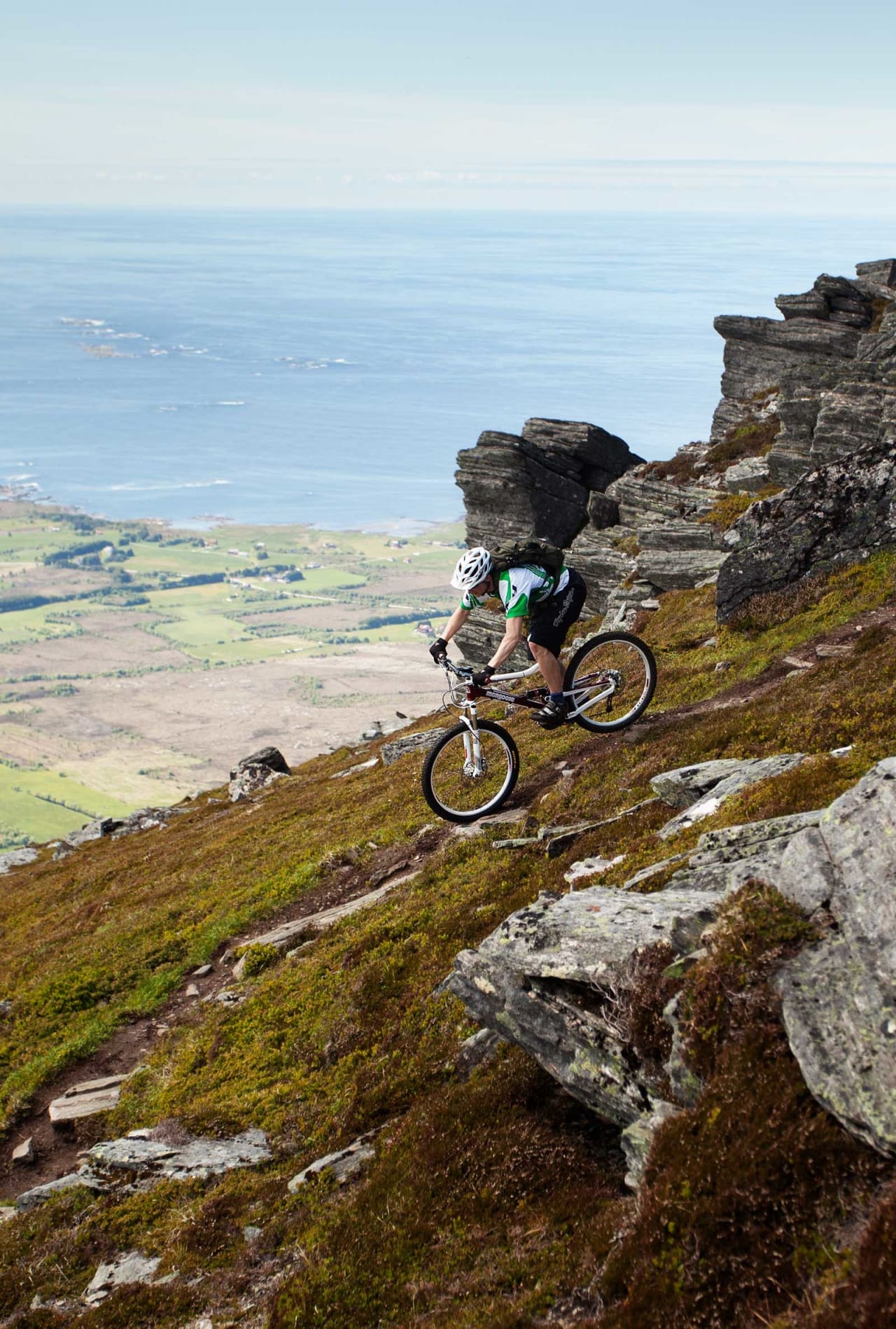Mathias Marley sykler ned fra Sjurvarden med Hustadvika i bakgrunnen. / Stisykling i Norge.